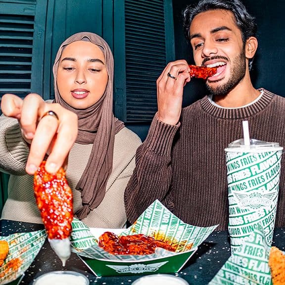 A man and woman eating chicken wings